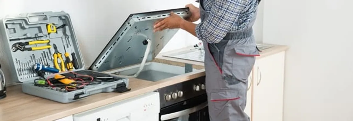 Cooktop repair technician lifting a built-in stovetop for service in Richmond, VA